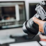 photographer hand camera and computer on desk